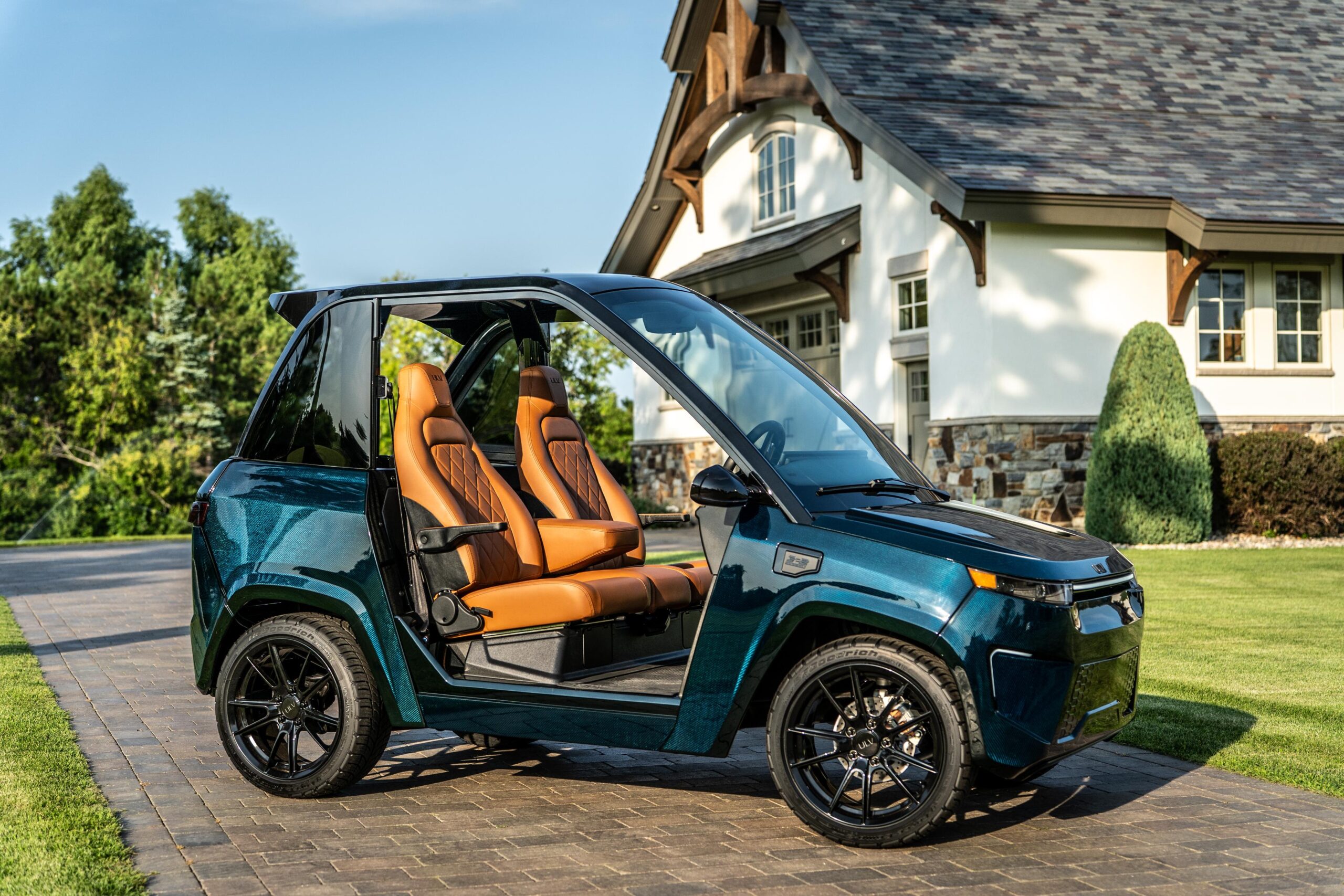 blue ulv 322 carbon parked in a driveway next to a large house