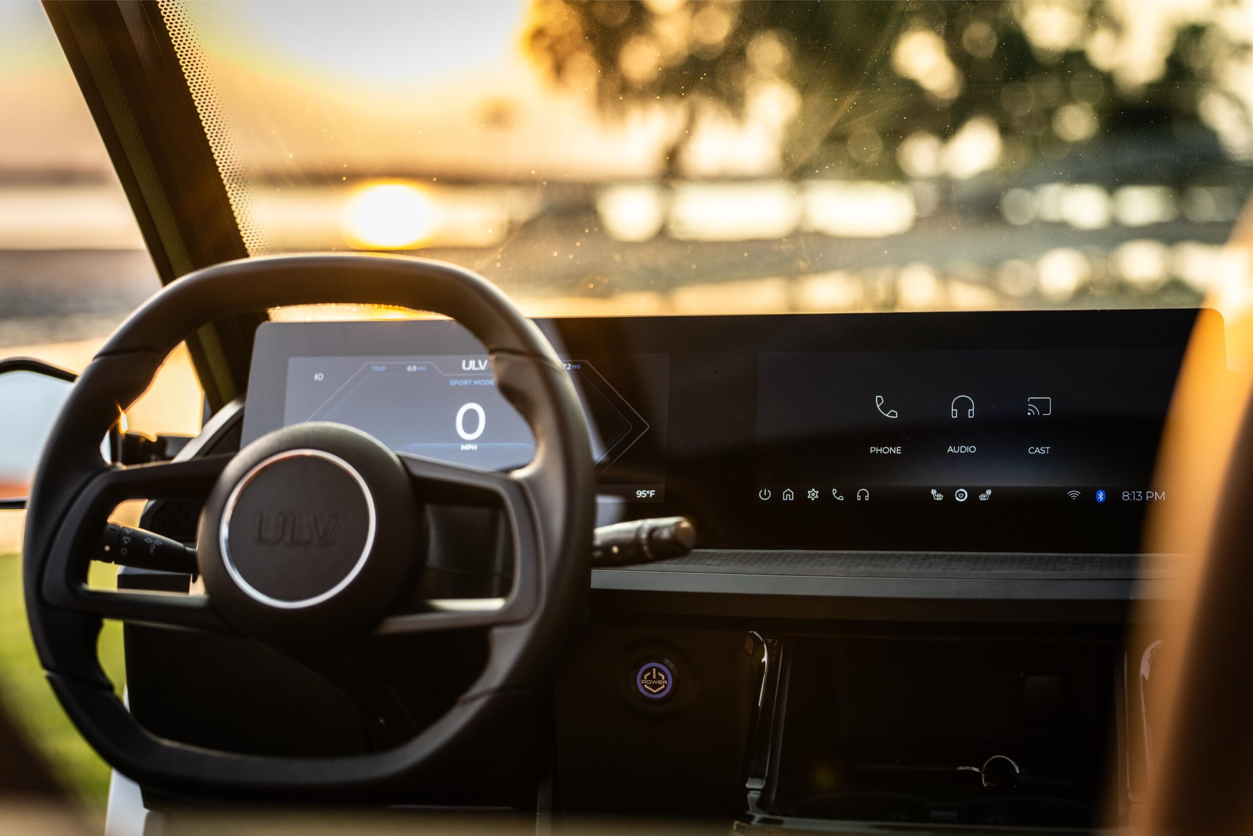 a shot of the ulv driver's dashboard including the steering wheel, touchscreen navigation and music controls and start button