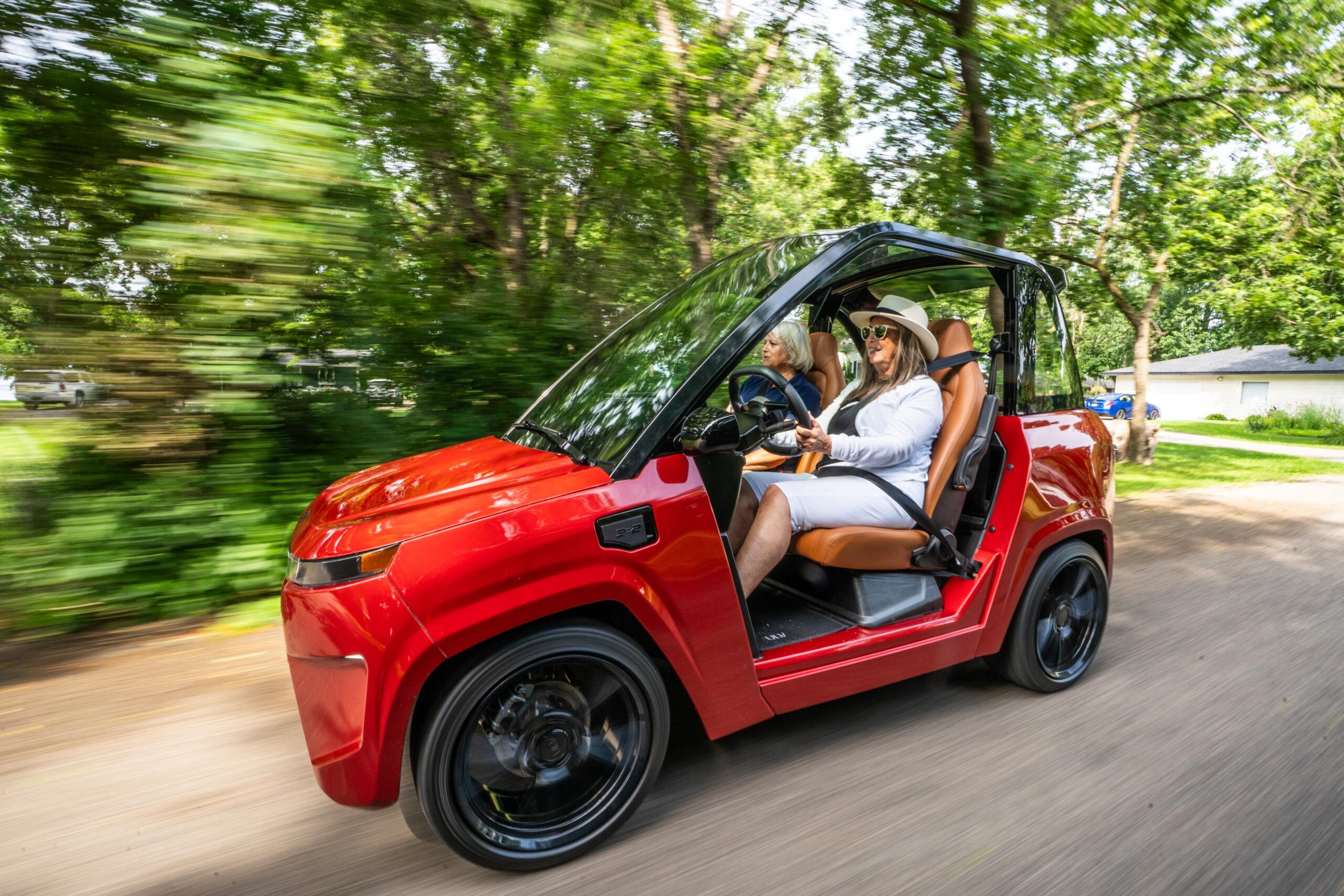 motion shot of two women in a red ulv 322 driving next to a wooded area
