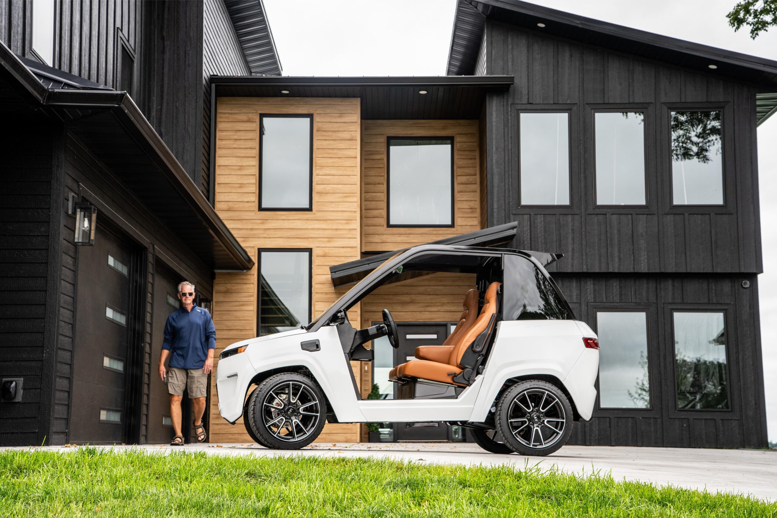 man walking up to a white ulv 322 parked in a driveway of a large house